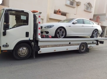 a towing servie in al khobar truck for flat rate towing in Rancho Cucamonga in action.  the tow truck is carrying a car on top